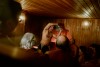 Nackte Menschen von hinten. in zwei Reihen sitzend, in einer finnischen Sauna. Der Aufgussmeister und Schauspieler Guido Drell wedelt energisch und aggressiv mit dem Handtuch