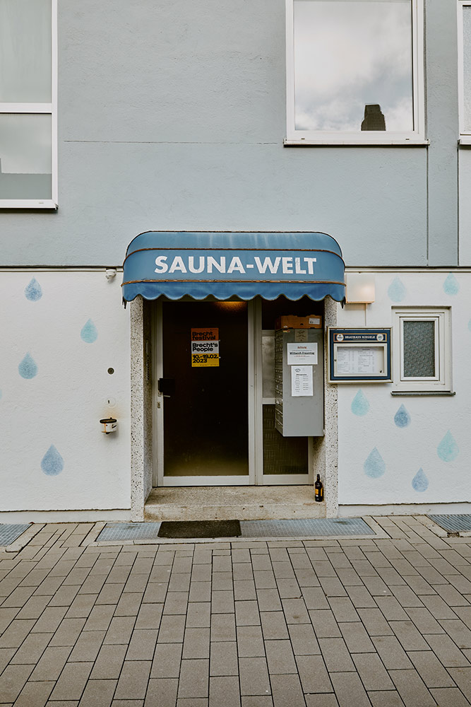 Im Foto ist der Eingang zur Sauna. Darüber ist eine blaue Markise mit dem Schriftzug "SAUNA-WELT"