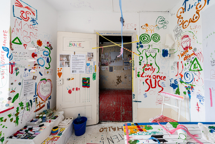 Auf dem Foto ist ein weißer Raum zu sehen, der an allen Wänden mit bunten Farben bemalt und beschrieben ist.